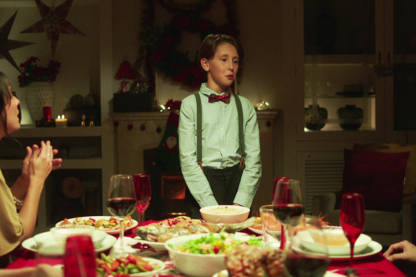 Niño delante de la mesa de cena de Navidad